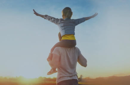 Photo d'un père qui porte sa fille sur le dos