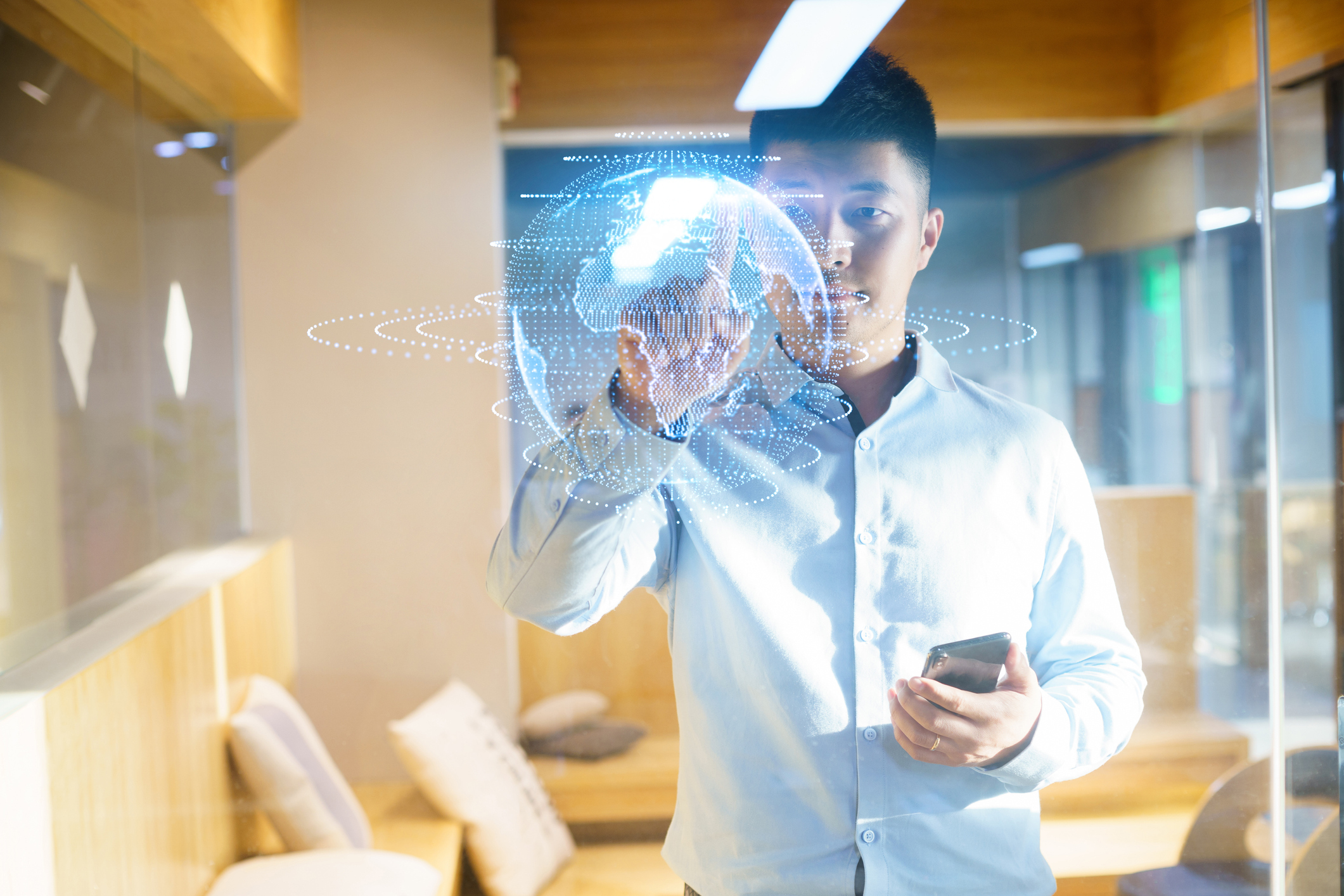 Visuel d'un homme asiatique utilisant un écran virtuel avec un téléphone portable au bureau