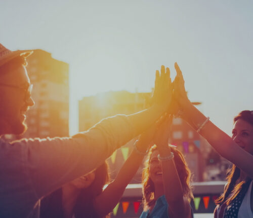 Photo de jeunes faisant un high-five au coucher du soleil.
